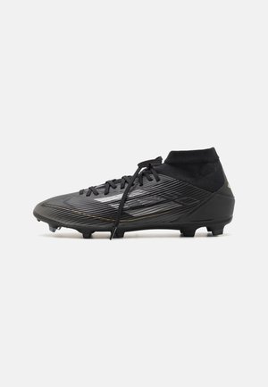 Chaussures de football noires avec dessus texturé, fermeture à lacets et design montant à la cheville. Présentent des lignes d'accent dorées et des crampons moulés sur la semelle.