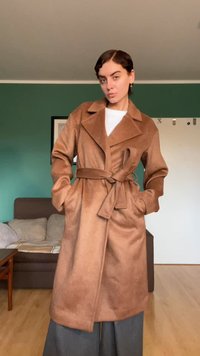 Bruine trenchcoat met ceintuur van zachte stof, met een brede reverskraag, lange mouwen en twee zakken aan de voorkant. Draag het over een wit overhemd.