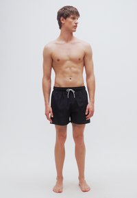 Μαύρα μαγιό σορτς από ελαφρύ υλικό, με ελαστική μέση, ρυθμιζόμενο κορδόνι και χαλαρή εφαρμογή.