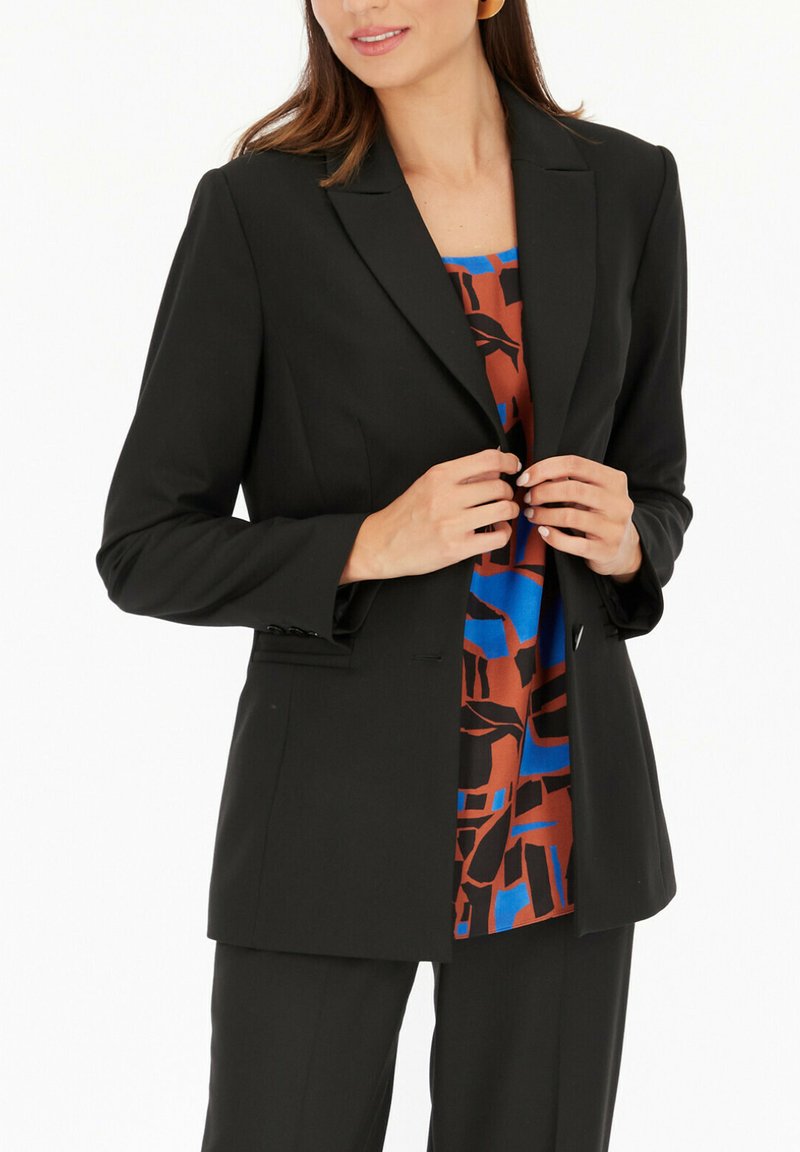 Czarna żakiet stylizowany na miarę, zapinany na pojedynczy guzik, z szpiczastymi klapami i długimi rękawami. Wewnątrz znajduje się kolorowy, abstrakcyjny wzór w odcieniach niebieskiego i brązowego.