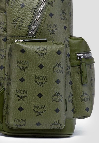 Zaino in pelle verde con loghi neri MCM e motivi a diamante, dotato di scomparti con zip e superficie testurizzata per una maggiore durata.