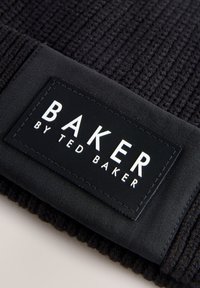 Black knitted beanie with a woven texture. Features a rectangular label with "BAKER BY TED BAKER" in white on a black background.