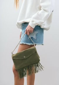 Olive green suede handbag with fringe detail at the bottom, featuring a clasp closure and a silver chain strap.