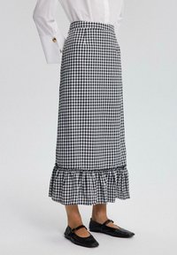 Černobílá gingham midi sukně s volánkovým lemem. Vyrobeno z tkané látky, s přiléhavým pasem a jemným nařasením na spodní části.