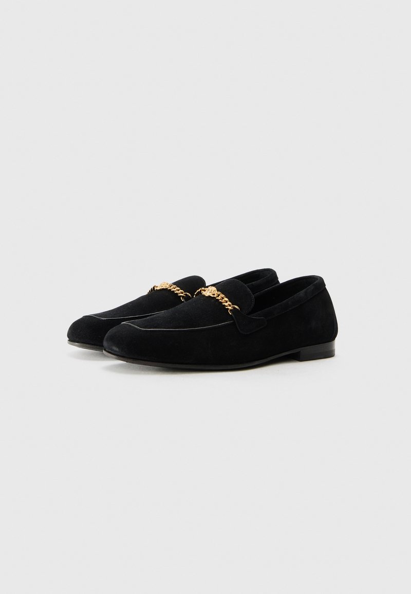 Mocassins en velours noir avec un détail de chaîne dorée à l'avant. Le design comprend un bout légèrement pointu et un talon plat.