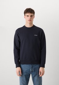 Sudadera de color azul marino hecha de una tela suave, con un cuello redondo, puños acanalados y un pequeño logo bordado de "BOSS" en el lado izquierdo del pecho.