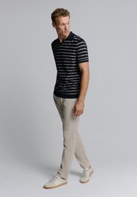 Marine gestreept polohemd met korte mouwen, gecombineerd met lichtbeige pantalons en witte sneakers. Eenvoudig design, katoen materiaal, ontspannen pasvorm.