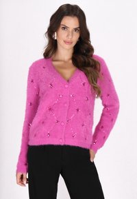 Flauschige, pinke Strickjacke mit V-Ausschnitt, sechs Knöpfen und Paillettenblumenverzierungen. Weicher Stoff mit langen Ärmeln.