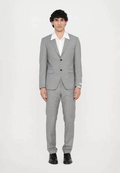 Lys grå dragt, enkeltstående jakke med to knapper, slim fit bukser, hvid skjorte, sorte sko, glat tekstur, ingen mønstre eller accenter.