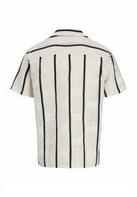 Chemise à col courte avec des manches courtes, couleur crème, ornée de rayures verticales noires. Motif texturé avec des formes de losanges et des détails de tricot ajouré.