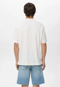 Hvid bomulds t-shirt med korte ærmer, rund hals og en afslappet pasform, parret med lyseblå denim shorts med baglommer.