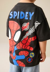 Schwarzes Baumwoll-T-Shirt mit einem großen roten und blauen Spider-Man-Motiv und dem Schriftzug "SPIDEY" in leuchtendem Blau auf der Rückseite.