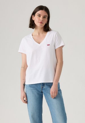 White cotton t-shirt with a v-neck and short sleeves, featuring a small red Levi's logo on the left chest. Worn with light blue jeans.