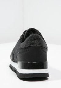 Černé sneakers s texturovanou tkaninou a kožen�ými detaily. Nízký profil, polstrovaná podrážka a lesklý černý podpatek. Bez viditelných log.