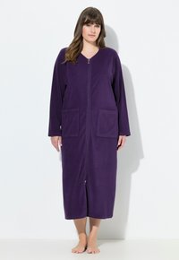 Fialový župan na zip vyrobený z měkké tkaniny, s dlouhými rukávy a dvoma předními kapsami, dosahující délky do poloviny lýtek.