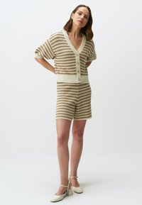 Das gestrickte zweiteilige Set besteht aus einem kurzärmligen, geknöpften Cardigan und passenden Shorts in Beige mit braunen horizontalen Streifen und geripptem Material.