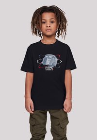 Schwarzbauchiges Baumwoll-T-Shirt mit einer Vintage-Grafik des Citroën H Vans, versehen mit "H 1947" und bunten Umlaufbahnen. Eine grüne Cargo-Hose ist sichtbar.