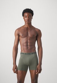 Ελαιόχρωμο μποξεράκι με μαύρη ζώνη "BJÖRN BORG". Μαλακό, ελαστικό ύφασμα με εφαρμοστή γραμμή και αντίθετα ραφές.