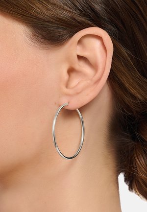 Silberner Creolen-Ohrring, runde Form, glatte Oberfläche, mittlere Größe, am Ohrläppchen befestigt, betont minimalistisches Design.