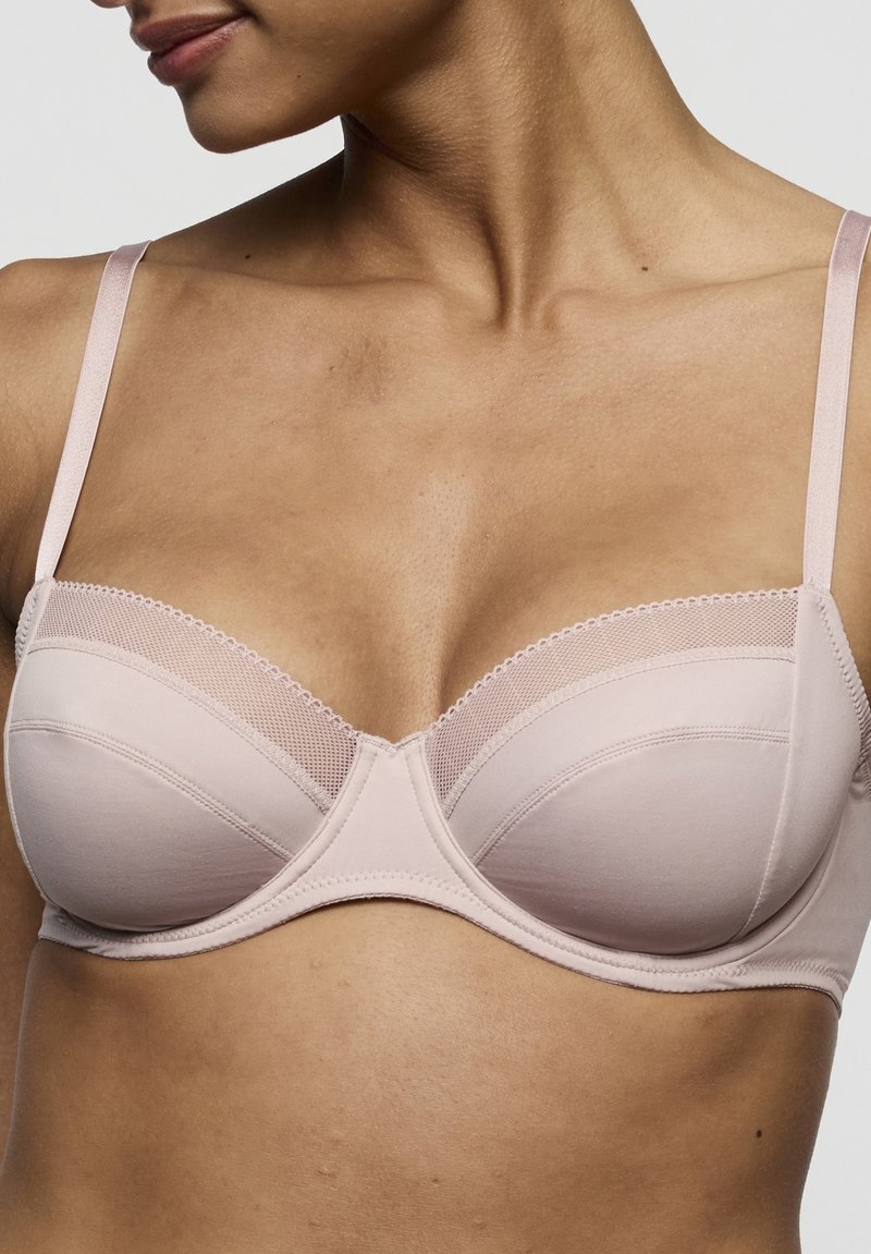 Soutien-gorge rembourré rose clair avec bretelles satinées ajustables. Présente un bord en dentelle le long du haut et une texture lisse. Conception avec armatures pour un meilleur maintien.
