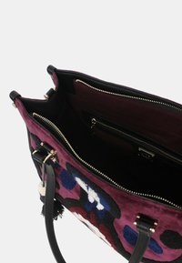 Borsa a mano in tessuto viola con motivi floreali, dettagli in pelle nera, doppi manici e chiusura con zip. L'interno include diverse tasche.