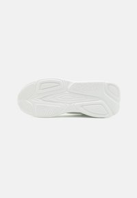 White sneaker sole with textured patterns, featuring grooves and ridges for traction. Logo "HUGO" embossed on the side.