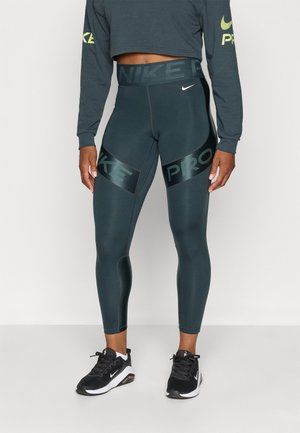 Nike Pro tights i mørkegrønn med høyt liv, med svarte paneler som har "NIKE" og "PRO" tekst. Glatt, elastisk materiale.