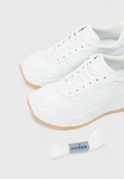 Scarpe da ginnastica bianche realizzate in pelle liscia, con suola in gomma e dettagli perforati. Include ulteriori stringhe bianche.