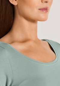 Mintgroene, getailleerde top met een ronde halslijn en korte mouwen, met een gladde, rekbare textuur en subtiele naden.