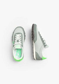 Graue Sneaker mit grünen Akzenten. Hergestellt aus Wildleder und Mesh, ausgestattet mit weißen Schnürsenkeln, einer strukturierten Gummisohle und Branding auf den Innensohlen.