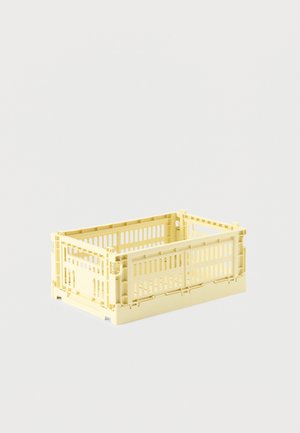 Rektangulær, blekgul plastkasse med ventilerte sider, sammenleggbar design og åpen topp, vist på en enkel lys bakgrunn.