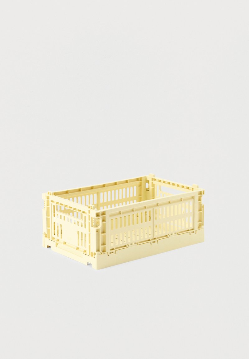 Caisse rectangulaire en plastique jaune pâle avec côtés ventilés, design pliable et dessus ouvert, présentée sur un fond clair uni.