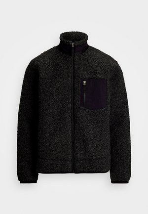Schwarze Fleecejacke mit hohem Kragen, Frontreißverschluss und einer kontrastierenden dunklen Tasche auf der linken Brust. Strukturiert Oberfläche und elastische Bündchen.