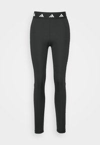 Melnas leggingas ar pieguļošu dizainu, izgatavotas no elastīga materiāla. Iespējas ietver jostasvītru ar balto Adidas logotipu un bezšuvju šuvju.