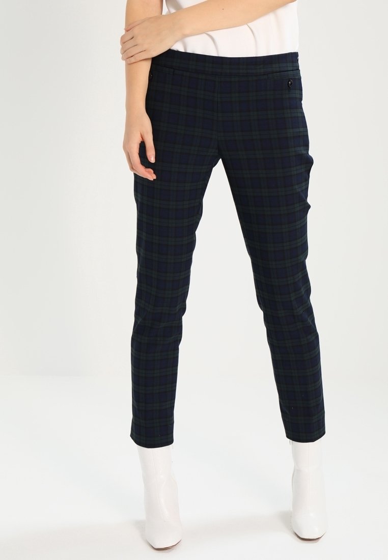 Svarta och gröna rutiga byxor med slim fit, med en stretchig midja och sidofickor, i kombination med vita ankelskor.