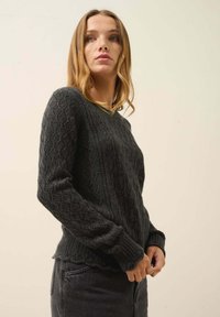 Tmavě šedý pletený svetr s diamantovým vzorem, s žebrovanými manžetami a kulatým výstřihem. Měkká textura a mírně volný střih.