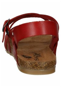 Sandalia de cuero rojo con parte trasera abierta, correa ajustable y plantilla de corcho. Presenta una suela plana y un diseño minimalista.