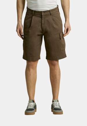 Uomo che indossa pantaloncini cargo marroni e sneakers grigie, in piedi con le mani rilassate lungo i fianchi su uno sfondo uniforme.