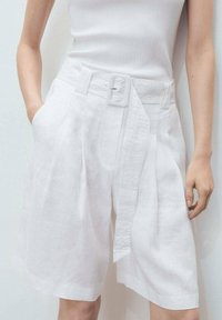 Des shorts en lin blanc dotés d'un design à jambes larges, de plis sur le devant, d'une taille ceinturée et de poches latérales. Texture lisse avec un aspect net.