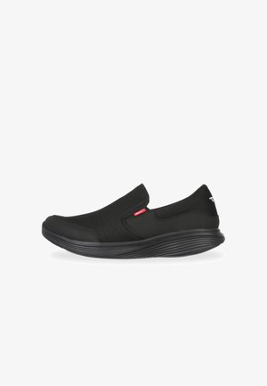 Zapatos negros tipo slip-on con parte superior de malla, punta redondeada, suela plana de goma y un sutil detalle de logo en rojo. Diseñados para ofrecer comodidad y facilidad de uso.