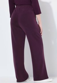Paarse wijde broek met een elastische tailleband, gemaakt van zachte stof. De textuur lijkt glad en is geschikt voor casual kleding.