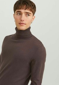 Maglione marrone a coste con colletto alto, realizzato in morbido tessuto lavorato a maglia. Presenta un design aderente e senza motivi o dettagli particolari.