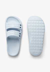 Light blue rubber slide sandals featuring two adjustable straps with perforations, a textured sole with a grid pattern, and a logo detail.