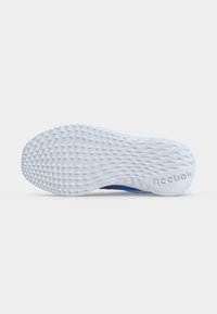 Λευκή υφασμάτινη σόλα παπουτσιού Reebok με τριγωνικό μοτίβο πέλματος και λογότυπο Reebok στη φτέρνα, εμφανίζεται σε απλό φόντο.