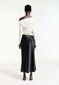 Un top alb off-the-shoulder asortat cu o fustă maxi din satin negru. Prezintă o textură netedă și o croială de lungime ankle. Pantofii cu toc bloc negri completează ținuta.