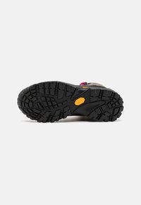 Schwarze Gummisohle mit tiefen Profilen, mit einem gelben "Vibram"-Logo. Hellbraunes Obermaterial mit rosa Akzenten und strapazierfähigen Beschlägen.