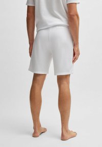 Witte katoenen shorts met een gestructureerde afwerking, voorzien van een relaxte pasvorm en een elastische tailleband. De stof is zacht en glad.