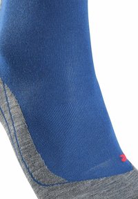 Blaue und graue Socke mit geripptem Muster, die einen grauen Fersenbereich und ein kleines rotes Logo an der Seite aufweist.
