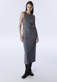 Vestido de punto acanalado gris con una silueta ajustada, detalles de encaje en los laterales y un dobladillo recto. El modelo lleva botas negras hasta la rodilla.