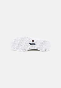 Suola in gomma bianca per sneaker con un motivo di battistrada testurizzato, un'etichetta antiscivolo e un design del tallone arrotondato.